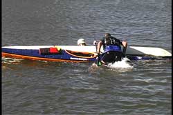 kayaks parallel with one upright and one paddler climbing on to back deck