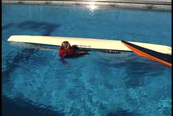 swimmer next to capsized kayak at cockpit