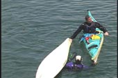 first paddler is completely upright holding the bow of the other kayak