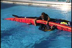 rescuer guiding feet into partially flooded edged kayak